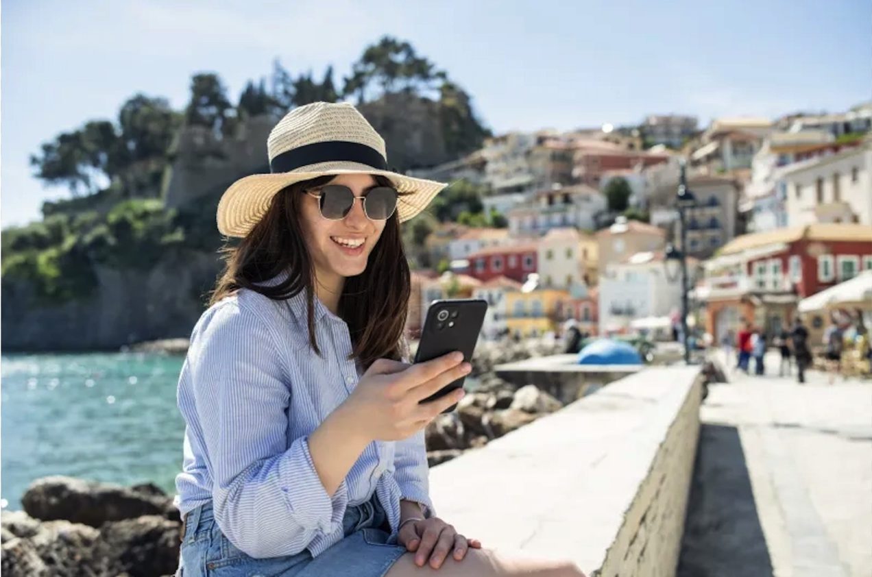 Traveler using a phone on a sunny waterfront